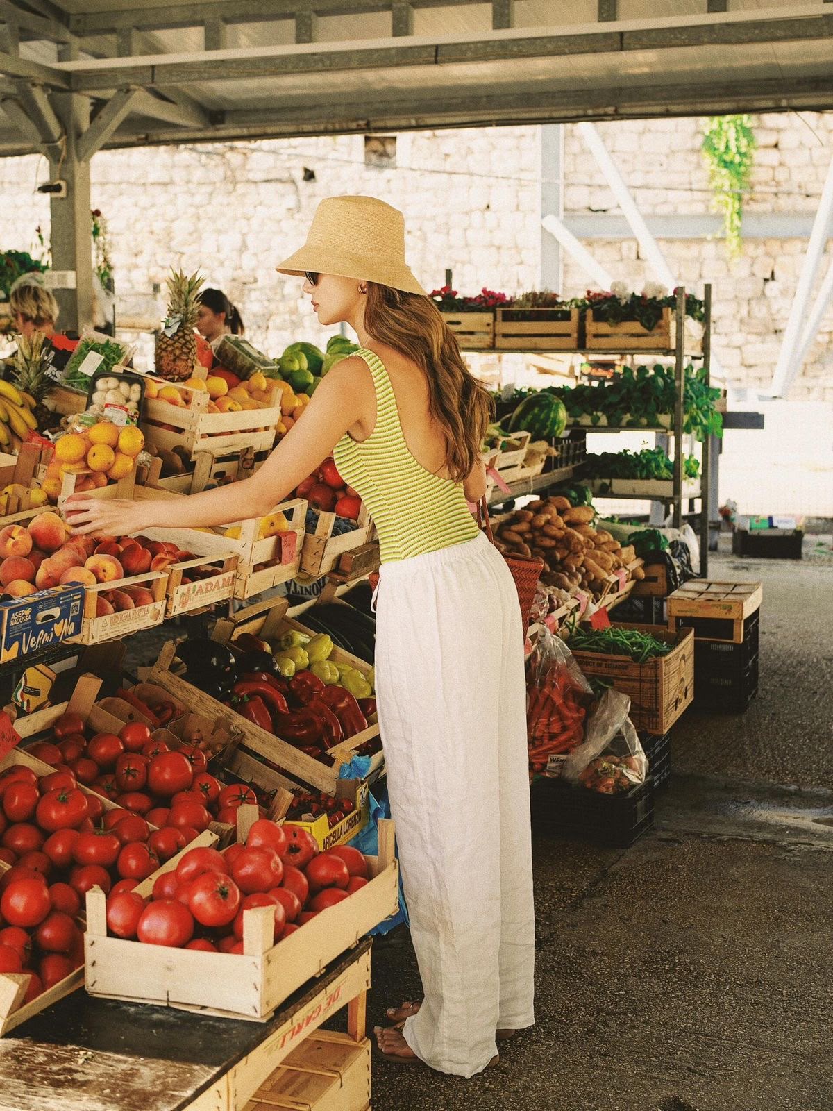 Femme choisissant des fruits sur un étal de marché ensoleillé